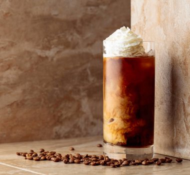 Kahve çekirdekli bej seramik masada kremalı buzlu kahve. Boşluğu kopyala.