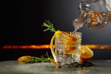 Limon ve biberiyeli cin tonik kokteyli. İçki şişeden buzlu bir bardağa dökülür. Boşluğu kopyala.