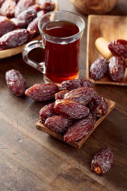 Cam bardakta çay ve eski ahşap bir masada hurma..