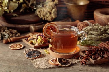 Bir fincan bitkisel çay, çeşitli kurutulmuş bitkiler, çiçekler ve baharatlar. İçindekilerle çay ve kurutulmuş portakal dilimleri..