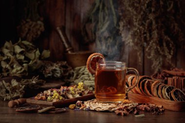 Bir fincan bitkisel çay, çeşitli kurutulmuş bitkiler, çiçekler ve baharatlar. İçindekilerle çay ve kurutulmuş narenciye..