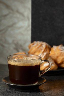 Cam bardakta sade kahve ve siyah taş masada kremalı kek. Boşluğu kopyala.