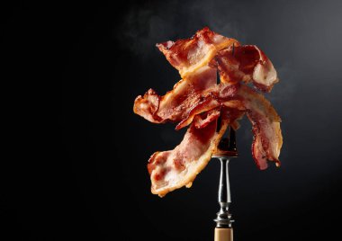 Siyah arka planda çatalda kızarmış pastırma. Boşluğu kopyala.