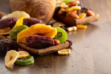 Kurumuş tropikal meyveler, çeşitli fındıklar ve kuru üzümler eski ahşap bir masada..
