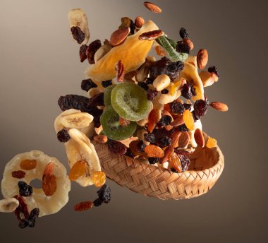 Çeşitli fındıklı kurutulmuş tropikal meyveler ve bej arka planda hareketli kuru üzümler. Boşluğu kopyala.