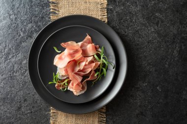 Prosciutto ve biberiye siyah bir masada. Üst görünüm. 