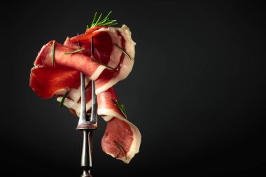 Çatal üzerinde biberiyeli dilimlenmiş jambon, siyah arkaplan, boşluğu kopyala.
