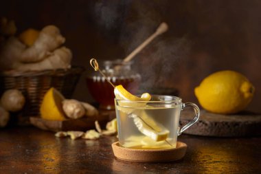 Kahverengi arka planda limonlu ve ballı zencefil çayı.
