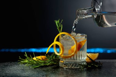 Limon ve biberiyeli cin tonik kokteyli. İçki şişeden buzlu bir bardağa dökülür. Boşluğu kopyala.