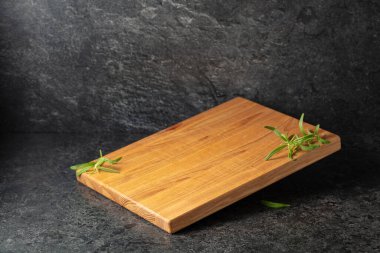 Siyah taşlı arka planda biberiyeli boş kesim tahtası. Boşluğu kopyala.