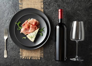 Bir şişe kırmızı şarap, mavi peynirli, jambonlu ve biberiyeli. Üst Manzara. Boşluğu kopyala.