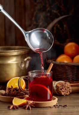 Sıcak şarap bir cam bardağa doldurulur. Eski ahşap bir masada malzemelerle birlikte sıcak şarap..