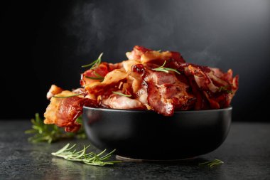 Siyah arka planda biberiyeli siyah bir tabakta kızarmış pastırma..