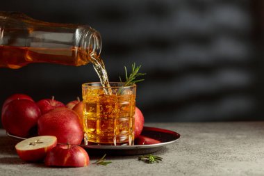 Elma suyu şişeden bardağa dökülür. Eski bir mutfak masasında elmalı taze içecek. Boşluğu kopyala.