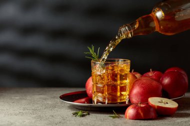 Elma şarabı şişeden bardağa dökülür. Eski bir mutfak masasında elmalı taze içecek. Boşluğu kopyala.