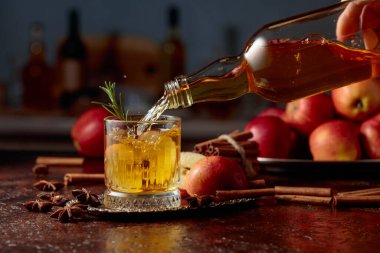 Elma şarabı şişeden kristal bardağa dökülür. Eski bir mutfak masasında elmalı taze içecek. Boşluğu kopyala.