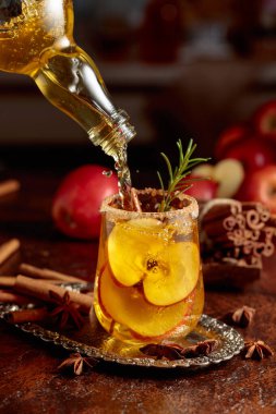 Elma şarabı şişeden bardağa dökülür. Eski bir mutfak masasında elmalı taze içecek..