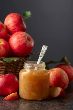 Elma reçeli ve kırmızı taze elmalar siyah taş bir masada..