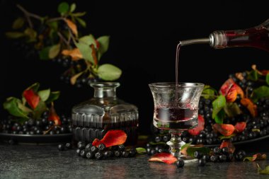 Siyah arka planda böğürtlen likörü ve taze böğürtlen. Meyve suyu ya da içki şişeden bardağa dökülür..