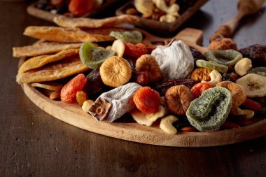 Kurutulmuş tropikal meyve, fındık ve kuru üzümlerin karışımı eski bir ahşap masada..