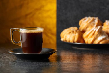 Cam bardakta sade kahve ve siyah taş masada kremalı kek. Boşluğu kopyala.