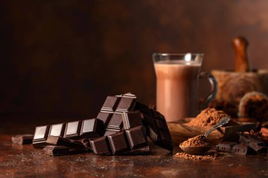 Kahverengi bir şarap masasında acı çikolata ve bir bardak kakao. Boşluğu kopyala.