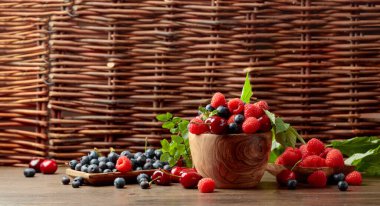 Çilek yakın çekim bahçede eski bir ahşap masada çilek, yaban mersini, ahududu ve tatlı kiraz karışımı renkli çeşitli. Yaprakları ile çeşitli sulu meyveler. Kopyalama alanı.