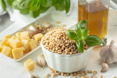 Pesto sosu yapmak için gerekenler: fesleğen, çam fıstığı, sarımsak, parmesan ve ahşap zemin üzerinde zeytin yağı. Geleneksel İtalyan pesto tarifi.