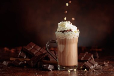 Krem şantili sıcak çikolata içeceği. Cam bardakta kakao ve koyu kahverengi arka planda acı çikolata..