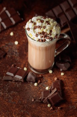Krem şantili sıcak çikolata içeceği. Cam bardakta kakao ve koyu kahverengi arka planda acı çikolata..