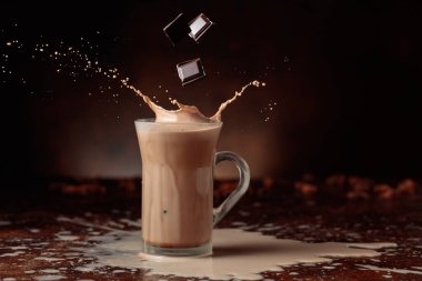 Acı çikolata parçaları cam bardağa dökülür kakao içeceği ile güzel su sıçratır. Boşluğu kopyala.