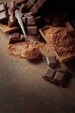 Kırık çikolata ve kahverengi paslı arka planda kakao tozu..