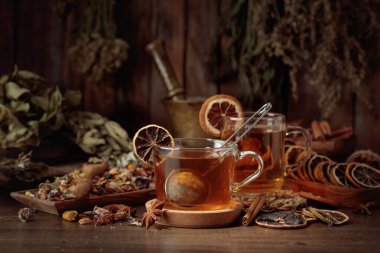 Çeşitli kurutulmuş otlar, çiçekler ve baharatlarla dolu bir fincan bitki çayı. İçindekilerle çay ve kurutulmuş narenciye..