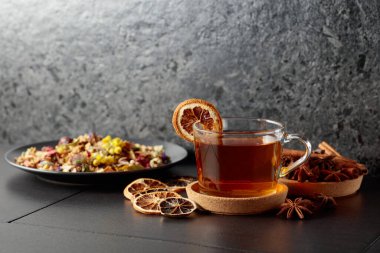 Bir fincan bitkisel çay ve siyah seramik bir masada kurutulmuş portakal dilimleri. Boşluğu kopyala.