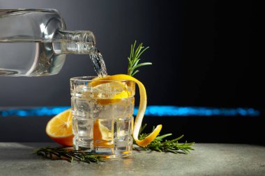 Limon ve biberiyeli cin tonik kokteyli. İçki şişeden buzlu bir bardağa dökülür. Boşluğu kopyala.