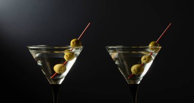 Siyah arka planda yeşil zeytinli klasik sek martini kokteyli. Metnin için boş yer.