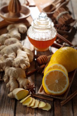 Zencefilli çay hazırlamak için gerekli malzemeler. Zencefil, limon, bal, anason ve tarçın çubukları eski bir mutfak masasında..