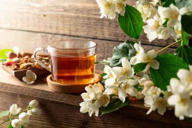 Tahta bir masada bitki çayı ve yasemin çiçeği dalı. Boşluğu kopyala.
