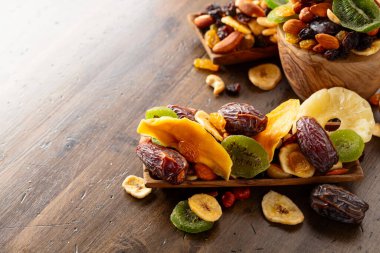 Kurumuş tropikal meyveler, çeşitli fındıklar ve kuru üzümler eski ahşap bir masada..