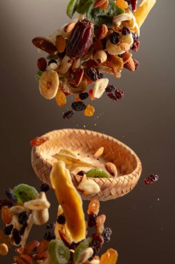 Çeşitli fındıklı kurutulmuş tropikal meyveler ve bej arka planda hareketli kuru üzümler. Boşluğu kopyala.