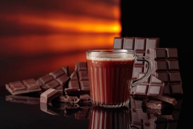 Sıcak çikolata ve kırık çikolata. Kopyalama alanı olan siyah yansıtıcı arkaplan.