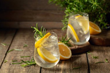 Eski ahşap bir masada buzlu, limonlu ve biberiyeli cin tonik. Boşluğu kopyala.