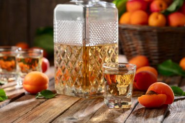 Apricot liqueur or grappa and fresh apricots on an old wooden table.