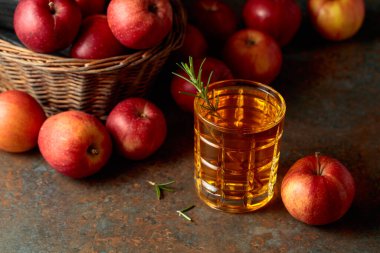 Elma suyu şişeden bardağa dökülür. Bir bardak meyve suyu ve taze elma eski bir mutfak masasında oturuyor..