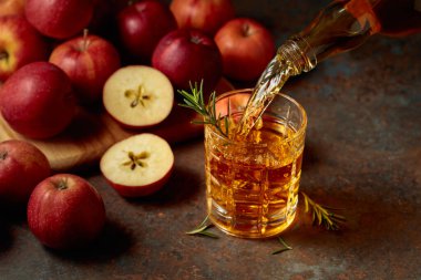 Elma şarabı şişeden bardağa dökülür. Eski bir mutfak masasında elmalı taze içecek..