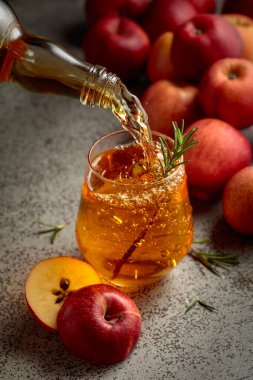 Elma şarabı şişeden bardağa dökülür. Eski bir mutfak masasında elmalı taze içecek. Seçici odak.