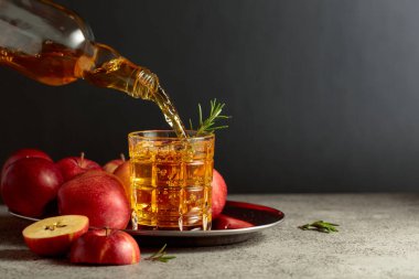 Elma şarabı şişeden bardağa dökülür. Eski bir mutfak masasında elmalı taze içecek. Boşluğu kopyala.