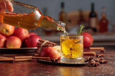 Elma şarabı şişeden kristal bardağa dökülür. Eski bir mutfak masasında elmalı taze içecek. Boşluğu kopyala.