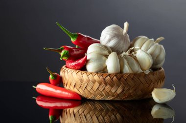 Siyah yansıtıcı arka planda sarımsak soğanları ve kırmızı biberler..
