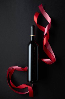 Bottle of red wine with red and pink satin ribbons. Top view. Copy space.